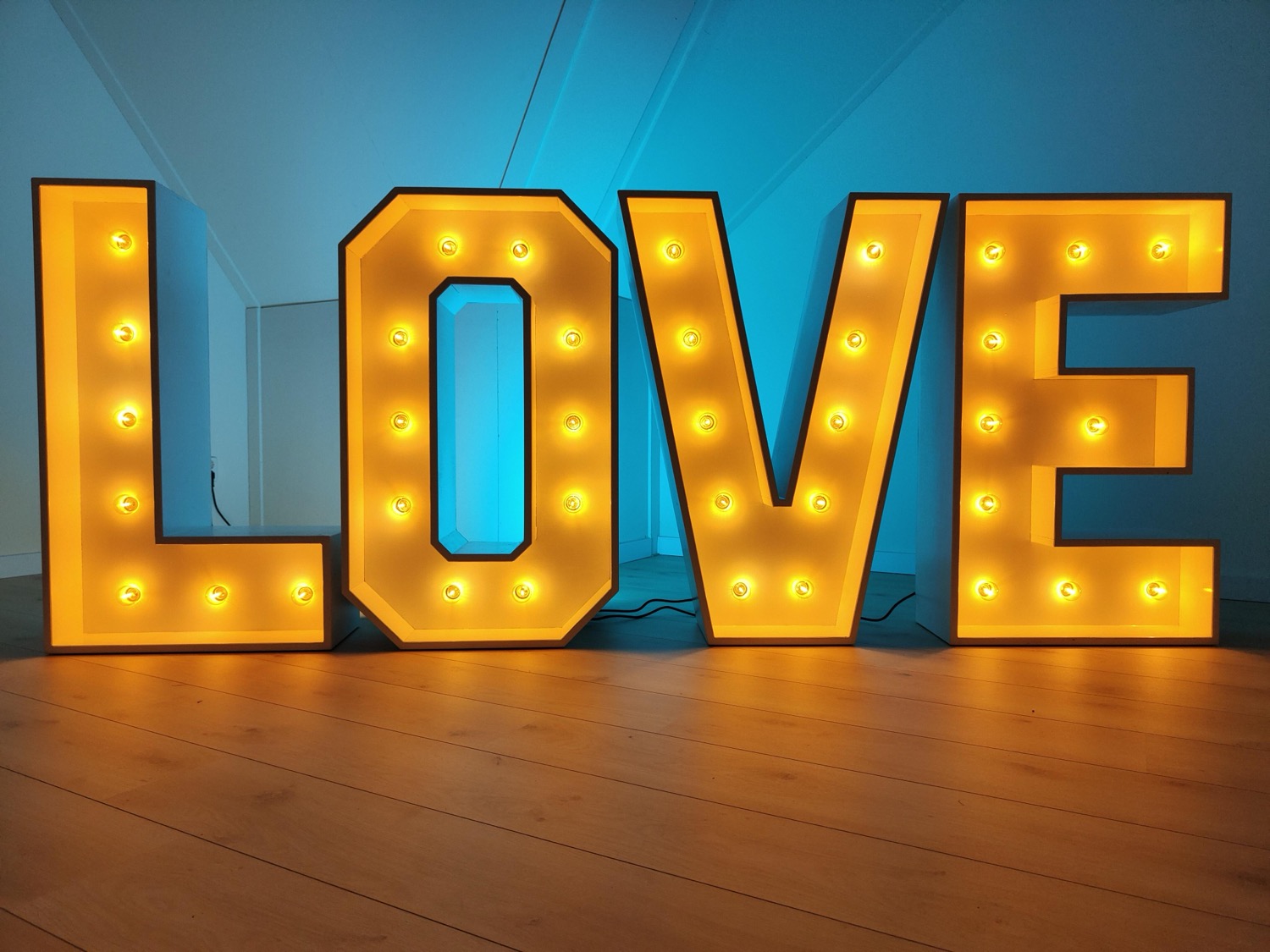 LOVE letters met warme LED-lampjes tegen een blauwe achtergrond