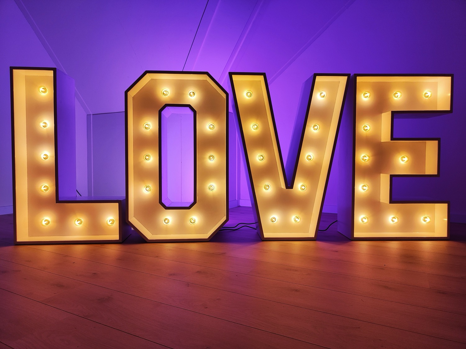 LOVE letters met LED-lampjes tegen een paarse achtergrond